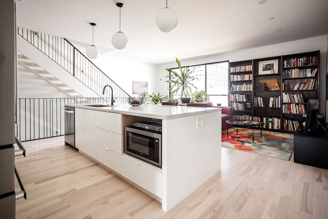 kitchen featuring white cabinetry, sink, an island with sink, pendant lighting, and appliances with stainless steel finishes