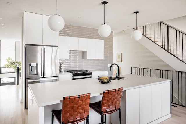 kitchen with a center island with sink, stainless steel appliances, and light wood-type flooring