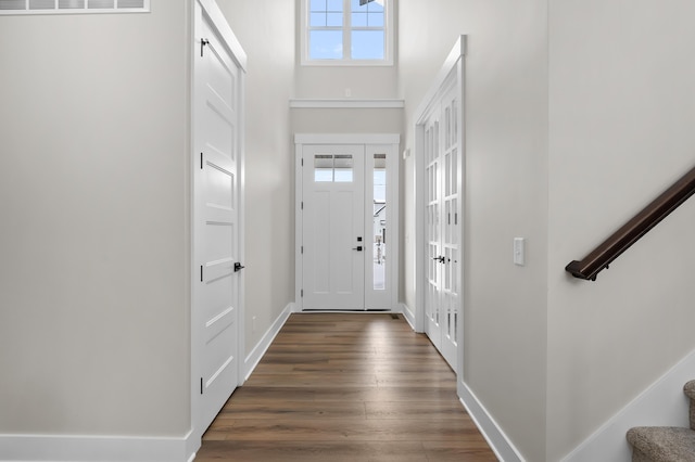 foyer featuring baseboards, stairway, dark wood-type flooring, and a wealth of natural light