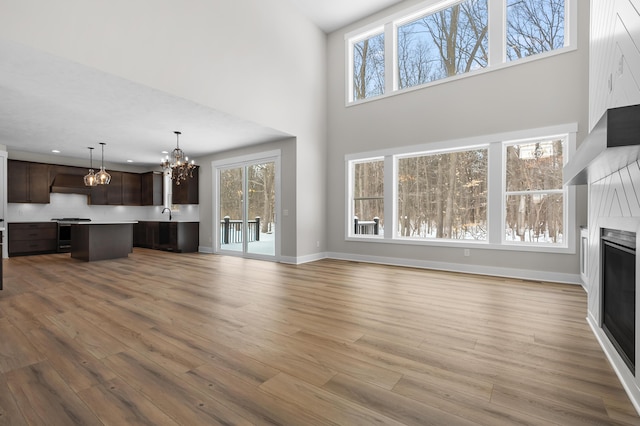 living room featuring baseboards, wood finished floors, an inviting chandelier, a high ceiling, and a fireplace