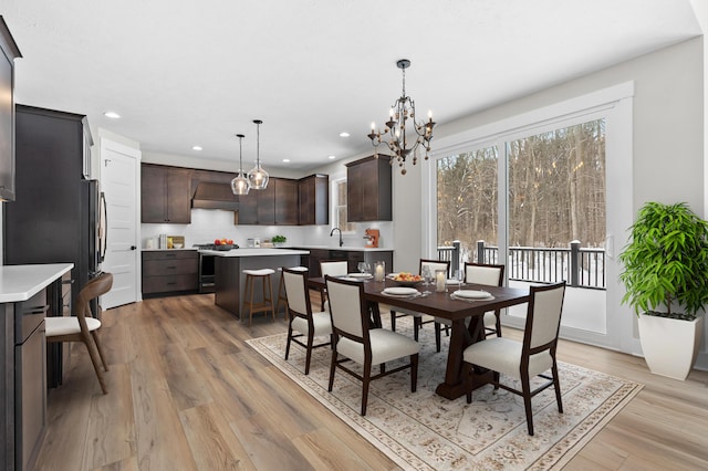 dining area with recessed lighting, a notable chandelier, and light wood-style flooring