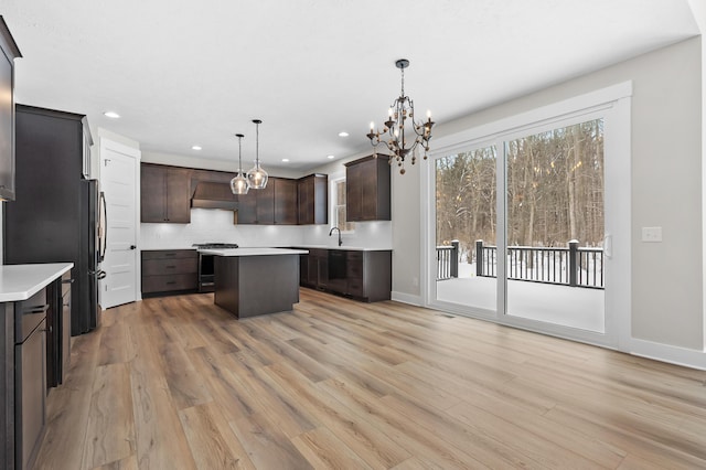 kitchen with light countertops, stainless steel range oven, a kitchen island, and decorative light fixtures