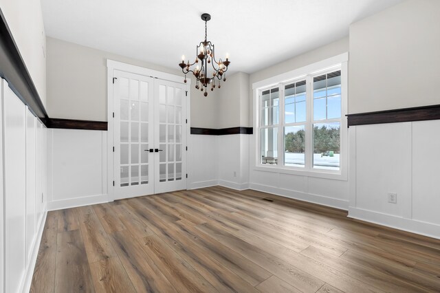 unfurnished dining area featuring baseboards, wood finished floors, and an inviting chandelier