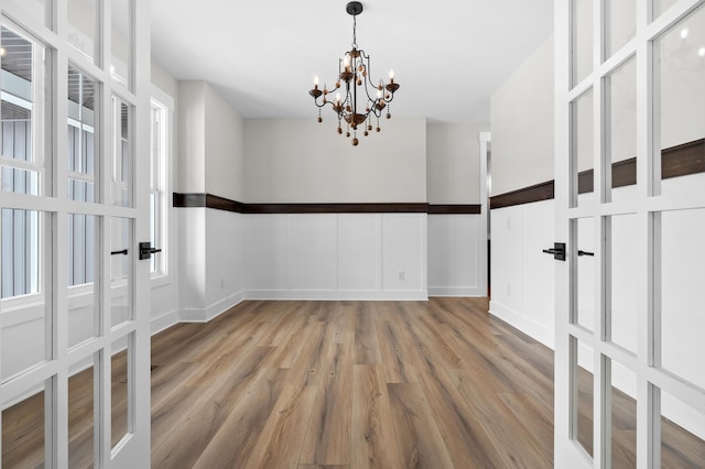 unfurnished room featuring a chandelier, a decorative wall, and wood finished floors