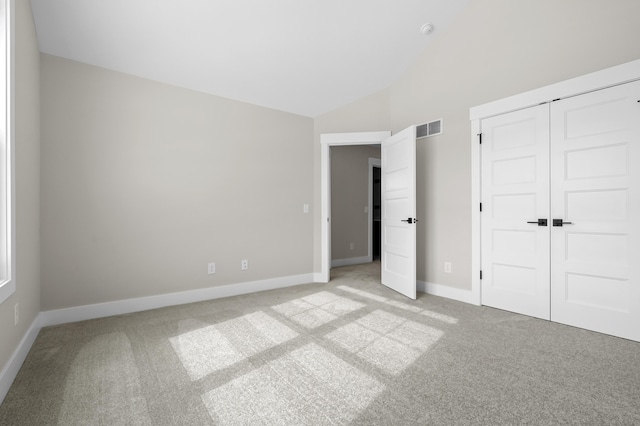 unfurnished bedroom featuring baseboards, visible vents, light colored carpet, high vaulted ceiling, and a closet