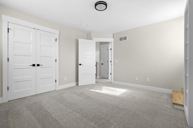 unfurnished bedroom featuring light carpet, a closet, visible vents, and baseboards