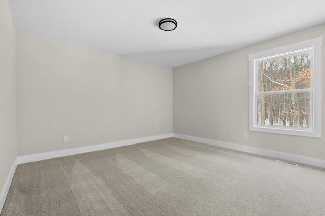 spare room with carpet floors, baseboards, and visible vents