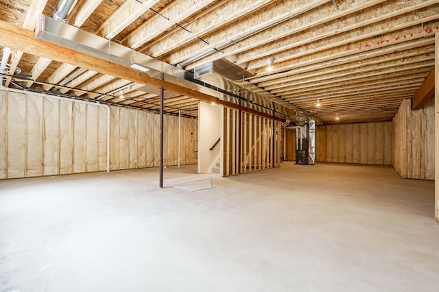 unfinished basement featuring stairway and heating unit