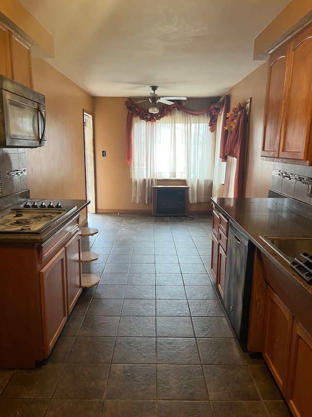 kitchen featuring backsplash, stainless steel dishwasher, cooktop, ceiling fan, and sink