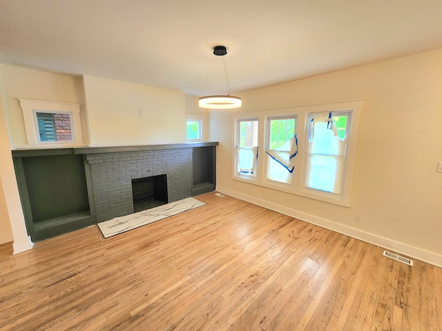 unfurnished living room with light hardwood / wood-style floors and a brick fireplace