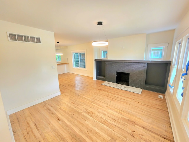 unfurnished living room featuring a healthy amount of sunlight, a fireplace, and light hardwood / wood-style floors