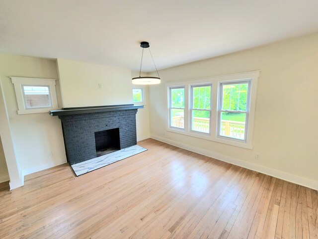 1645 Taylor St, Detroit, MI 48206 - unfurnished living room featuring a brick fireplace, baseboards, and light wood-type flooring
