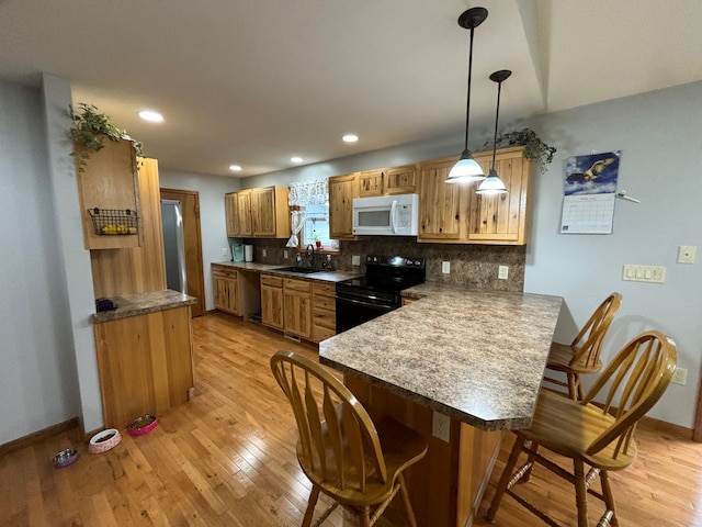 kitchen featuring sink, black range with electric stovetop, hanging light fixtures, tasteful backsplash, and kitchen peninsula