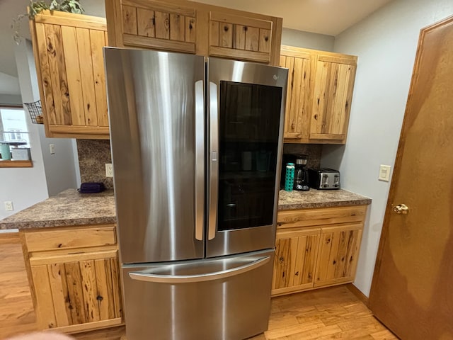 kitchen featuring tasteful backsplash, stainless steel fridge, and light hardwood / wood-style floors