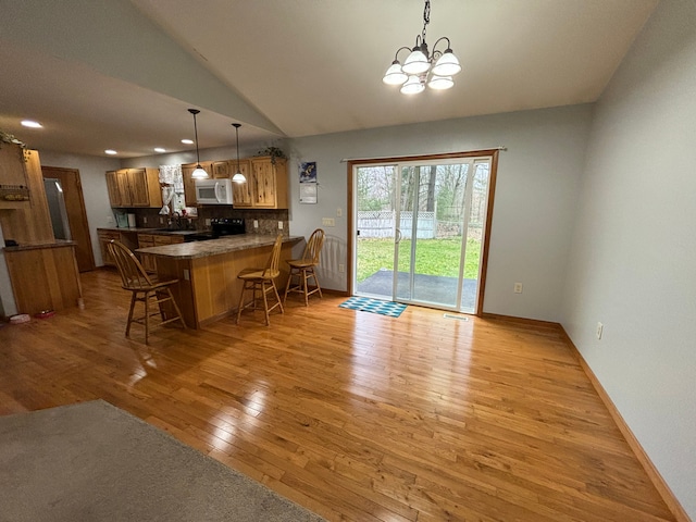 interior space with a breakfast bar area, light hardwood / wood-style flooring, electric range, kitchen peninsula, and decorative backsplash