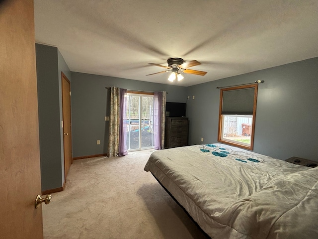 bedroom with ceiling fan, access to exterior, light carpet, and a textured ceiling