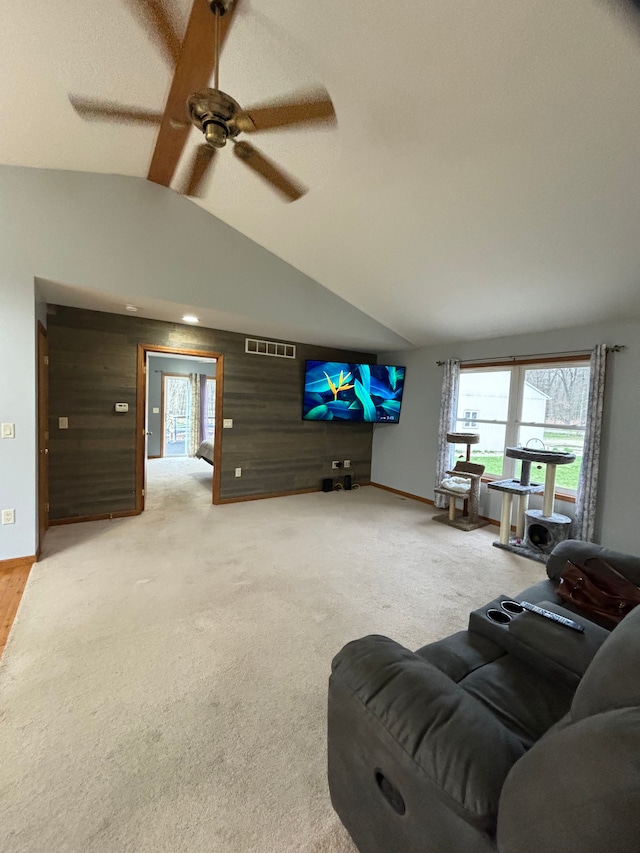 living room featuring high vaulted ceiling, light carpet, ceiling fan, and wood walls