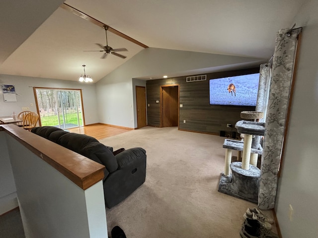 living room featuring ceiling fan with notable chandelier, lofted ceiling, carpet floors, and wood walls