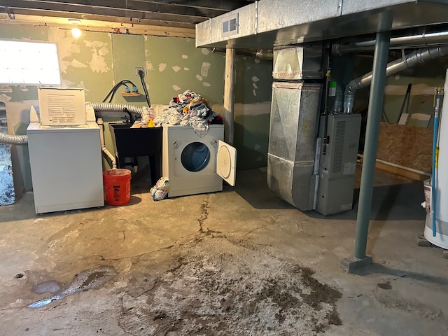 basement featuring heating unit, water heater, and washer and clothes dryer