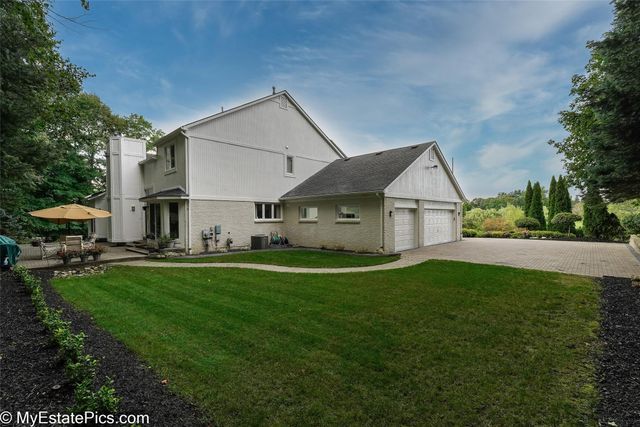 back of house featuring a lawn, a garage, and central AC