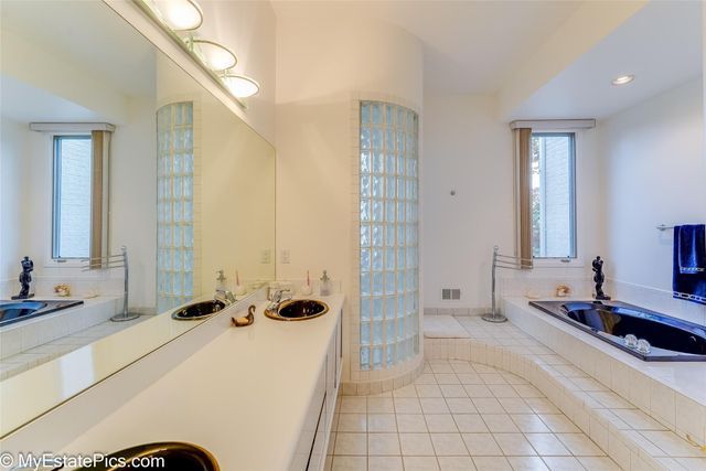 bathroom featuring tile patterned flooring, vanity, tiled bath, and a wealth of natural light