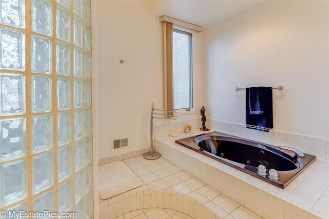 bathroom with tile patterned floors and tiled bath