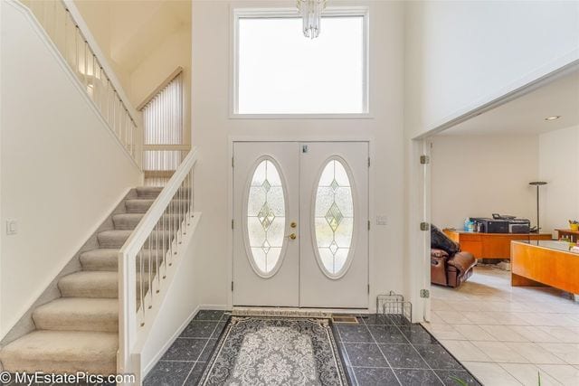 foyer with tile patterned floors, french doors, and a high ceiling