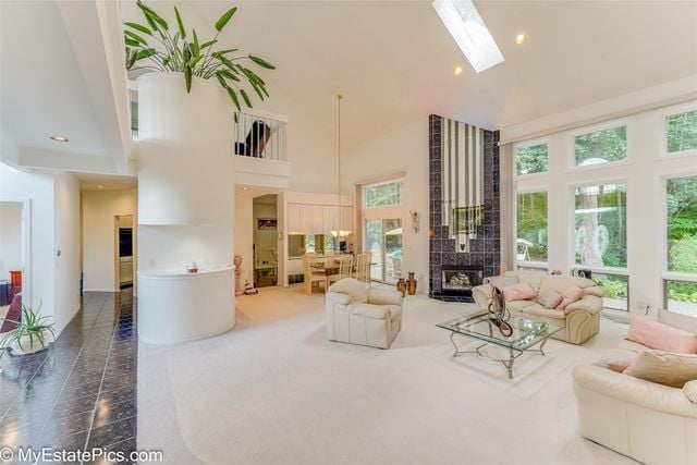 living room with a tile fireplace, a towering ceiling, and a skylight