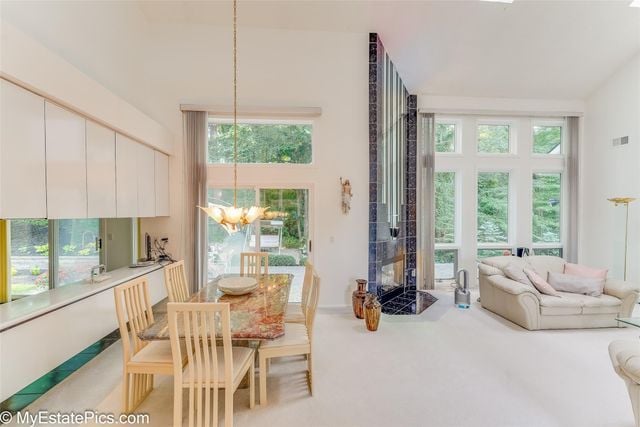 dining room featuring carpet floors, a notable chandelier, and a tiled fireplace