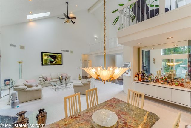 dining room with beam ceiling, light hardwood / wood-style flooring, high vaulted ceiling, and ceiling fan with notable chandelier