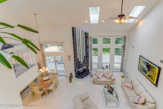 carpeted living room featuring ceiling fan, a wealth of natural light, and a skylight