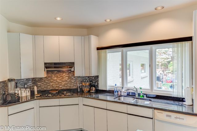 kitchen with dark stone countertops, sink, white cabinets, and white dishwasher