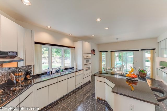 kitchen featuring backsplash, white cabinetry, a kitchen island, and sink