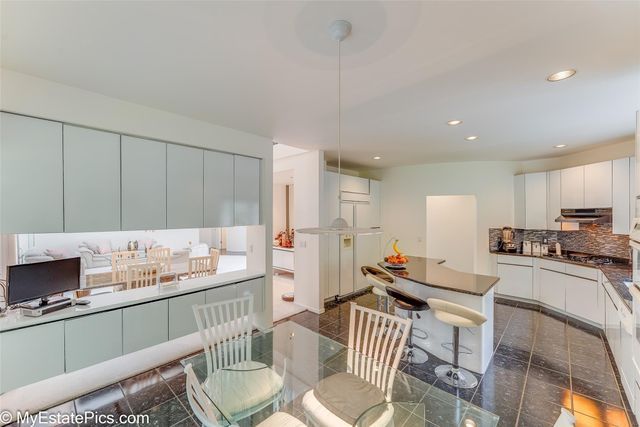 kitchen with decorative backsplash, white cabinets, and decorative light fixtures