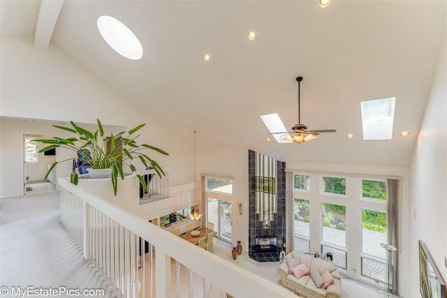 interior space with beamed ceiling, light colored carpet, high vaulted ceiling, and a skylight