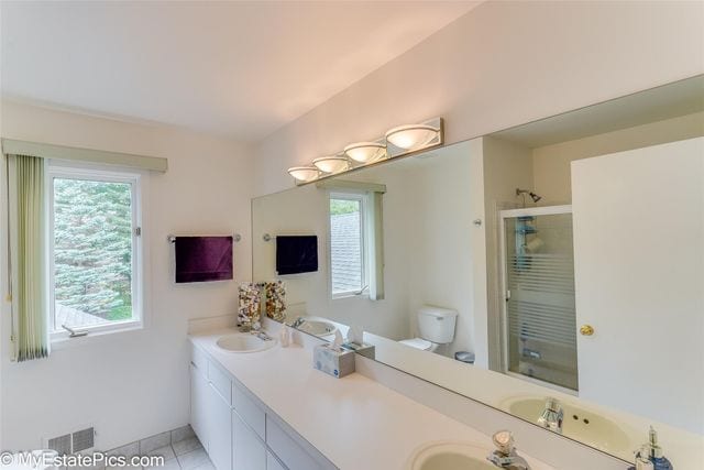 bathroom with tile patterned flooring, vanity, toilet, and a shower with door