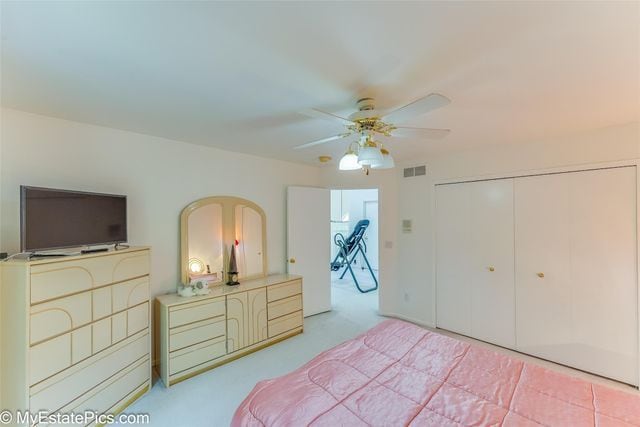 carpeted bedroom with ceiling fan and a closet