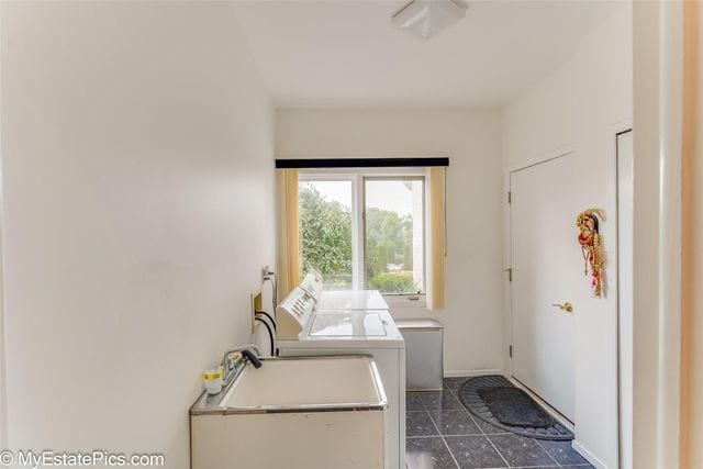 laundry area featuring washer and clothes dryer and dark tile patterned floors