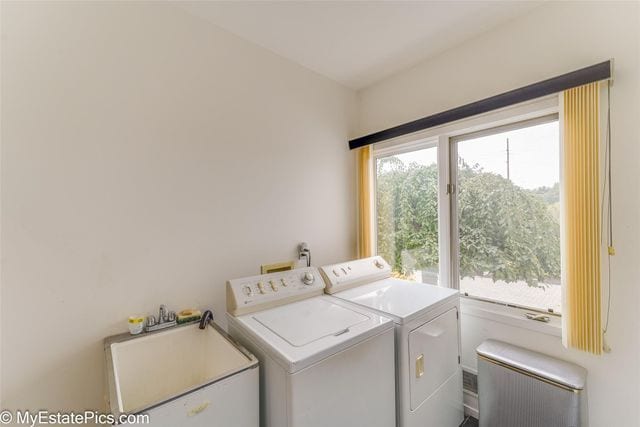 clothes washing area featuring a healthy amount of sunlight, separate washer and dryer, and sink