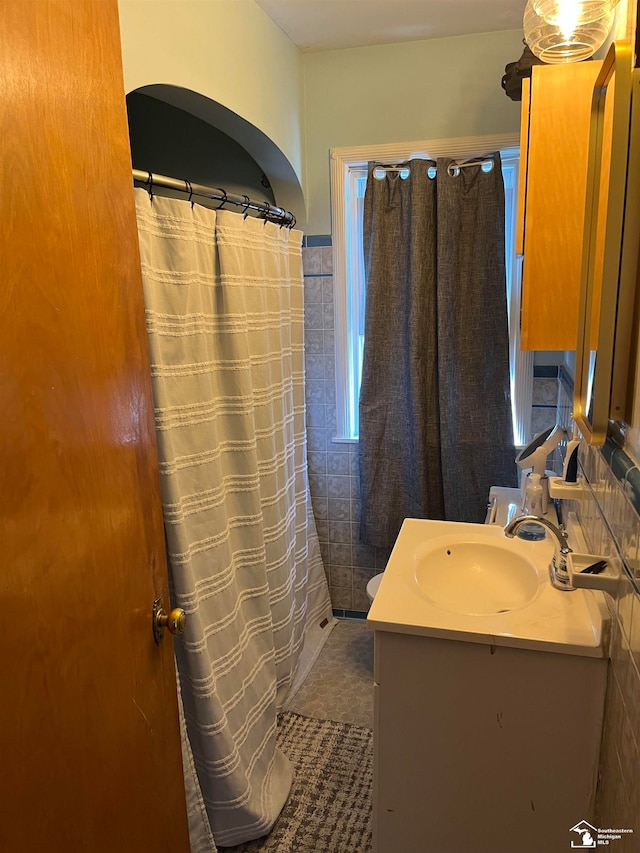 bathroom featuring tile patterned flooring, vanity, and tile walls