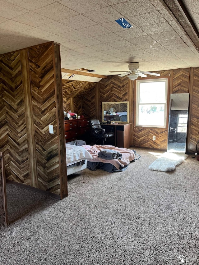 carpeted bedroom with ceiling fan and wooden walls