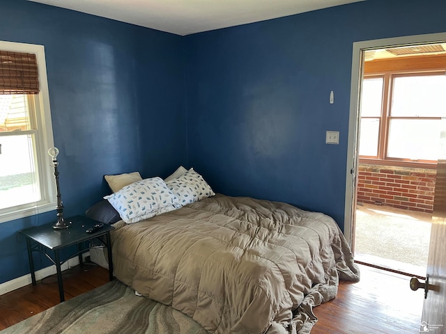 bedroom with hardwood / wood-style floors and brick wall