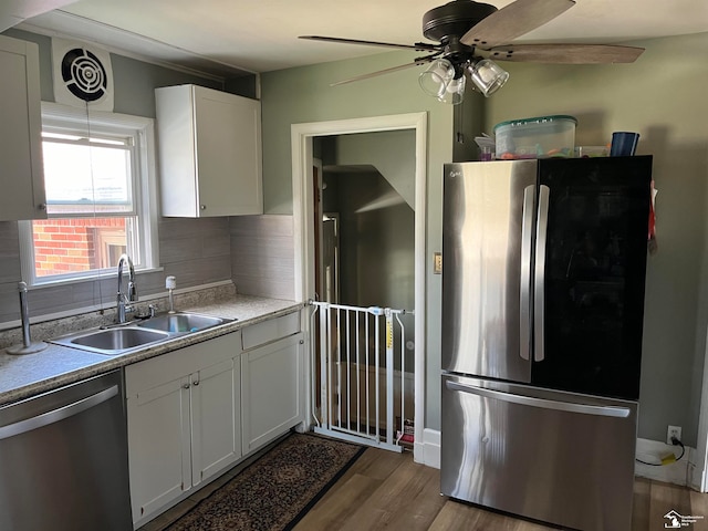 kitchen featuring decorative backsplash, light wood-type flooring, stainless steel appliances, sink, and white cabinetry