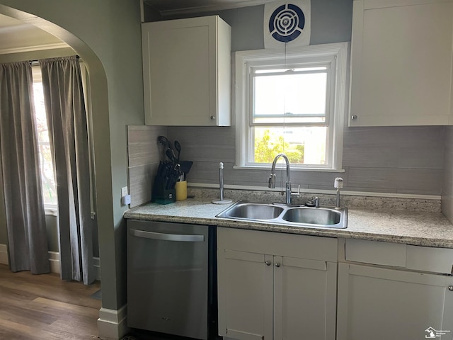 kitchen with tasteful backsplash, stainless steel dishwasher, sink, wood-type flooring, and white cabinetry