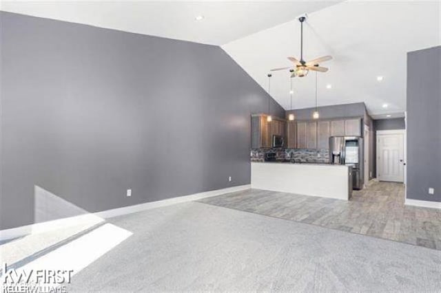 unfurnished living room featuring light carpet, high vaulted ceiling, and ceiling fan