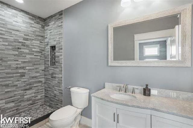 bathroom with vanity, toilet, and a tile shower