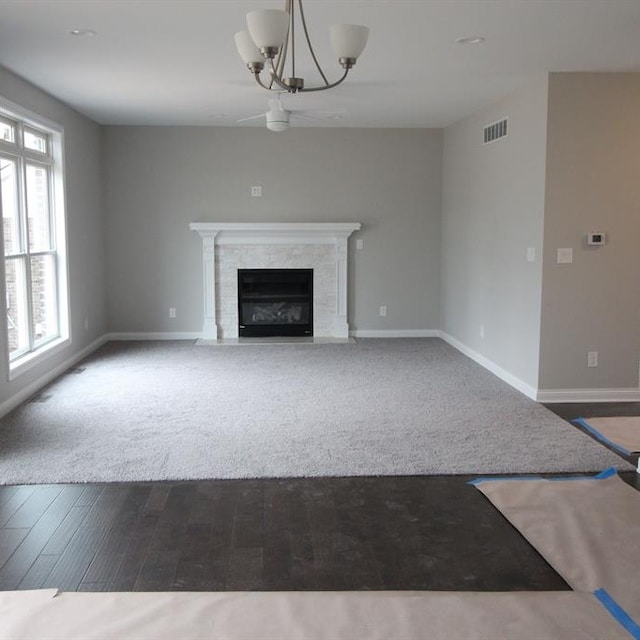 unfurnished living room featuring a chandelier and dark wood-type flooring