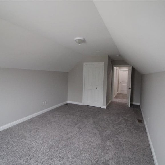 bonus room featuring dark carpet and lofted ceiling