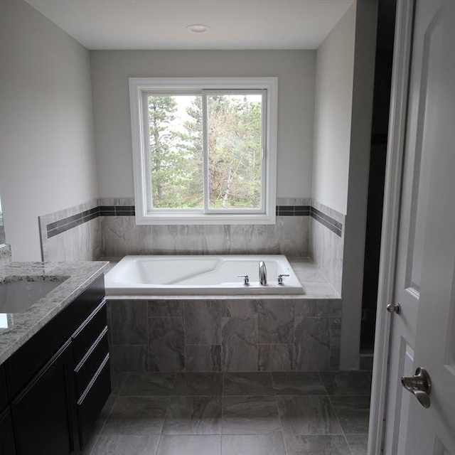 bathroom with tiled bath and vanity