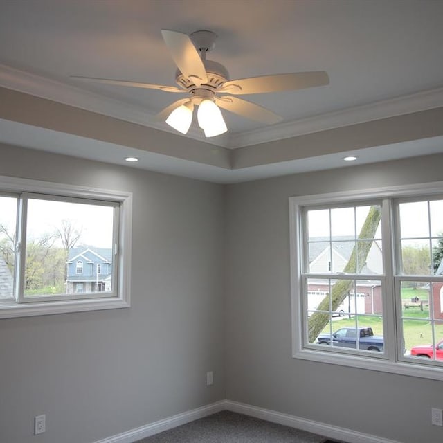 carpeted spare room featuring a wealth of natural light, crown molding, and ceiling fan